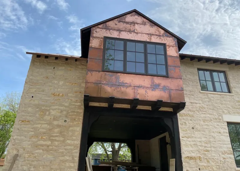 Copper metal panel facade on a stone building for Roof Repair in Kentwood