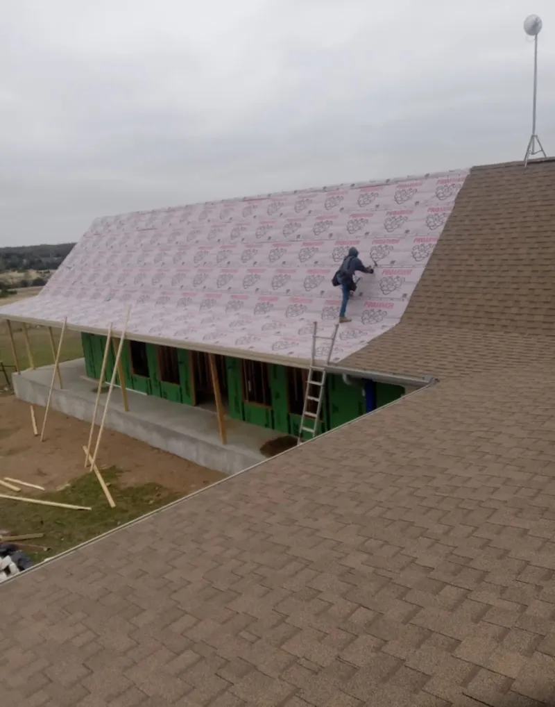 Worker preparing underlayment for a metal roof installation in Kentwood